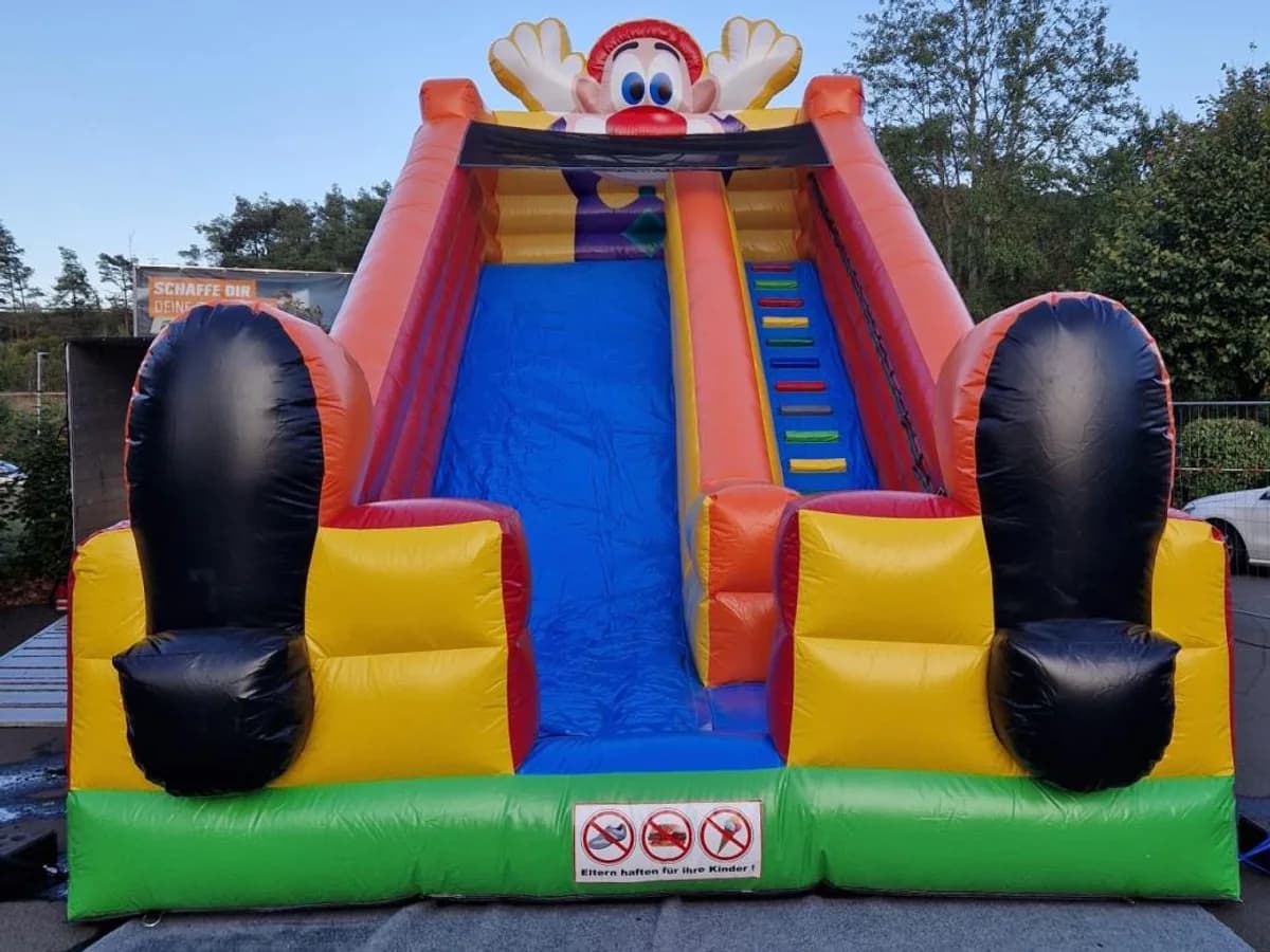 Rutschbahn mit lachendem Clownsgesicht und blauer Rutschfläche
