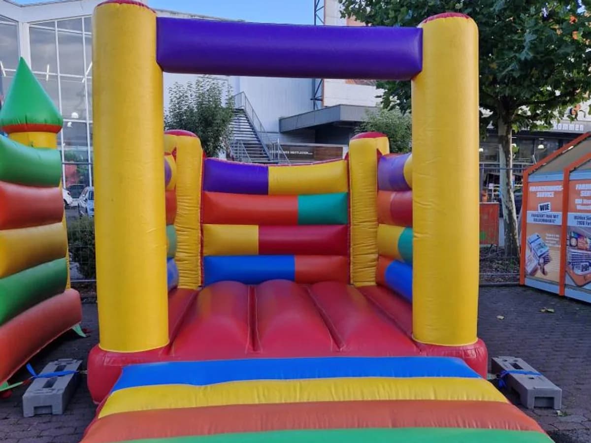 Bunte Hüpfburg mit gelben Eckpfosten und violettem Querbalken